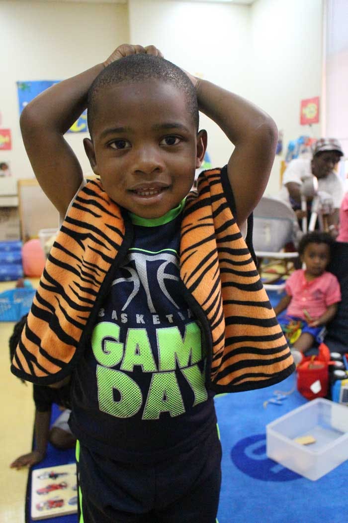 Child in a "Game Day" shirt with hands on head