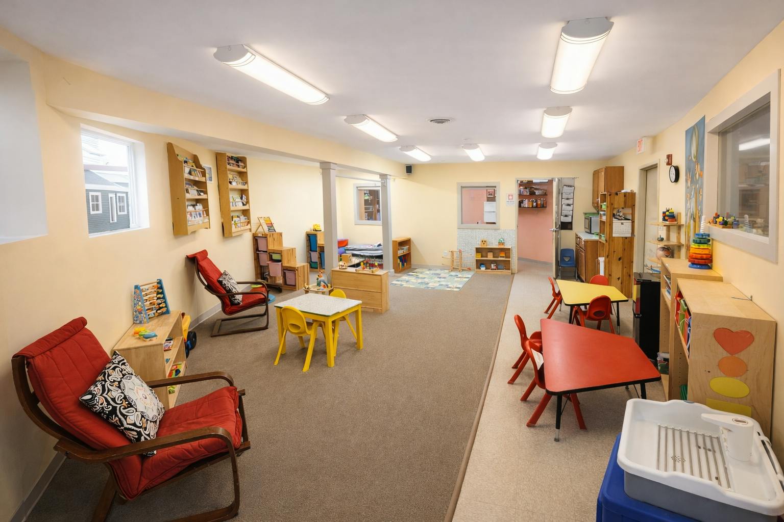 An empty early childhood classroom with small tables and chairs