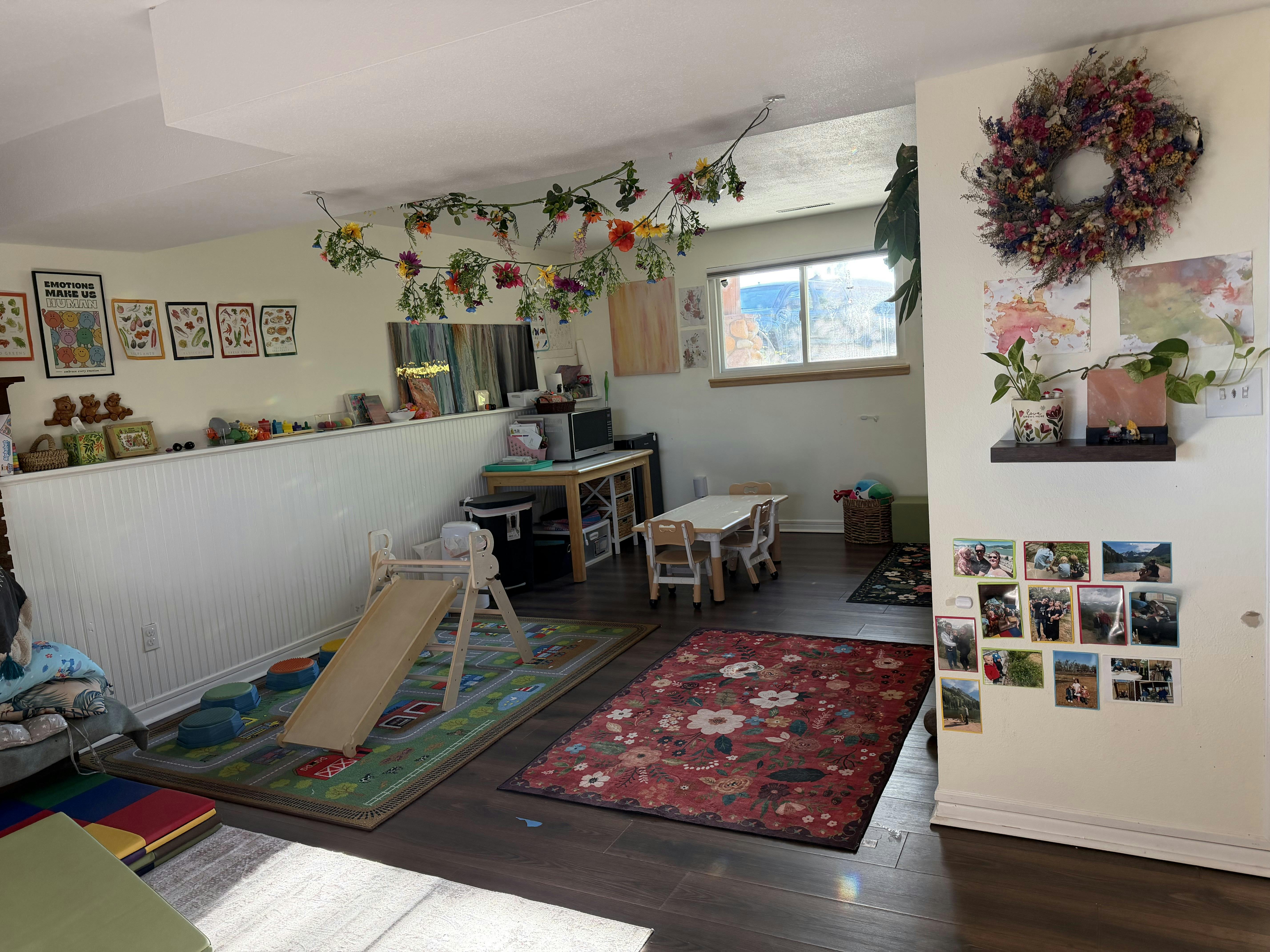 Playroom with a small wooden slide, child-sized table, and hanging flower decor