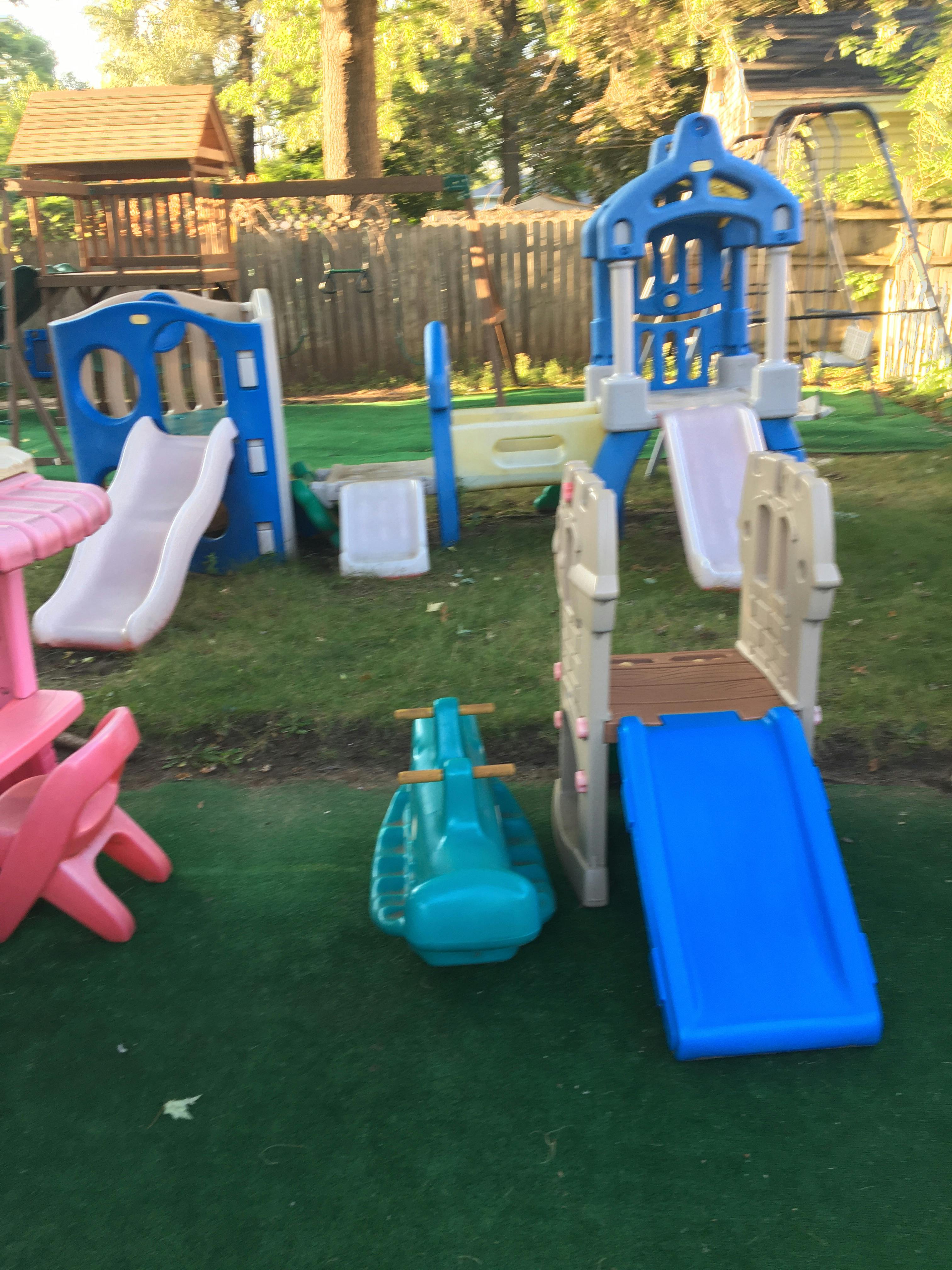 Playground with multiple slides and a rocking horse on artificial turf