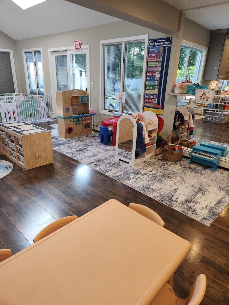 Childcare room with play kitchen, storage shelves, and a daily schedule chart