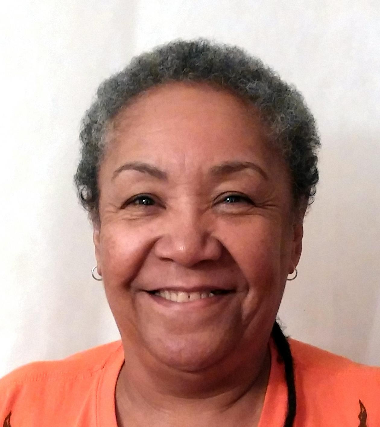 Close-up of a person with short curly hair and an orange shirt