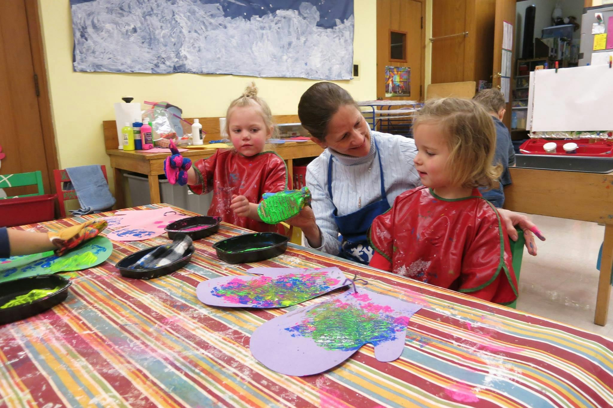 Adult and two children painting at a table