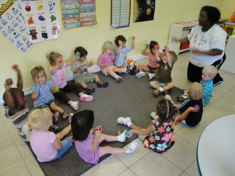Adult and children sitting in a circle on a rug in a classroom