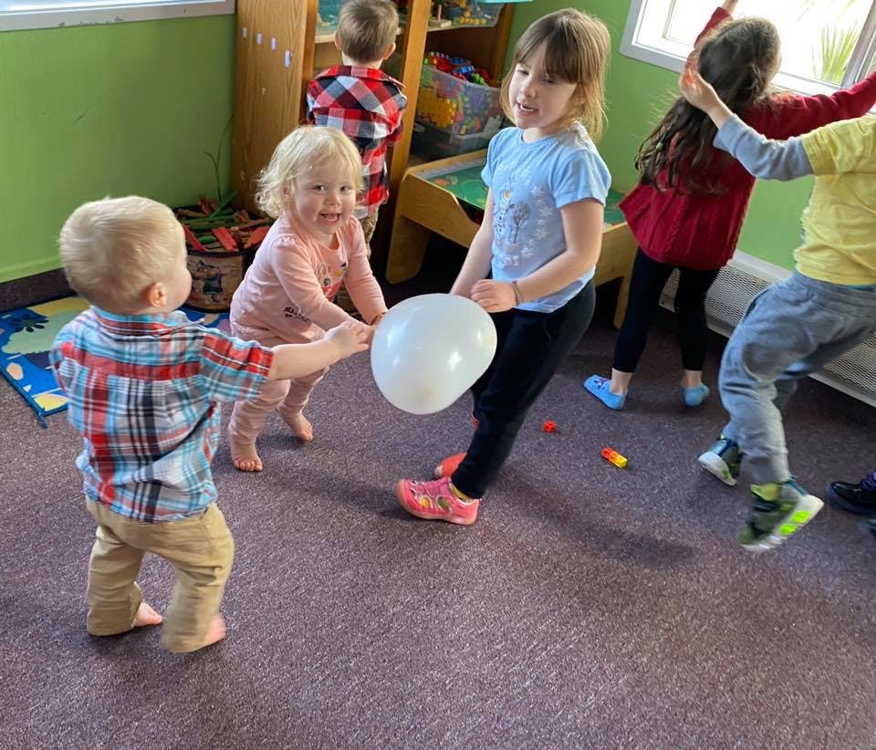 Children playing with a white balloon in a room