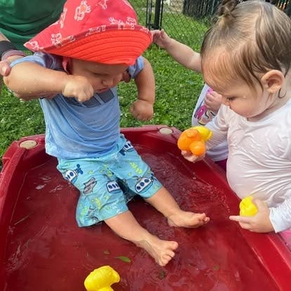 Two children playing with toys in a red water table