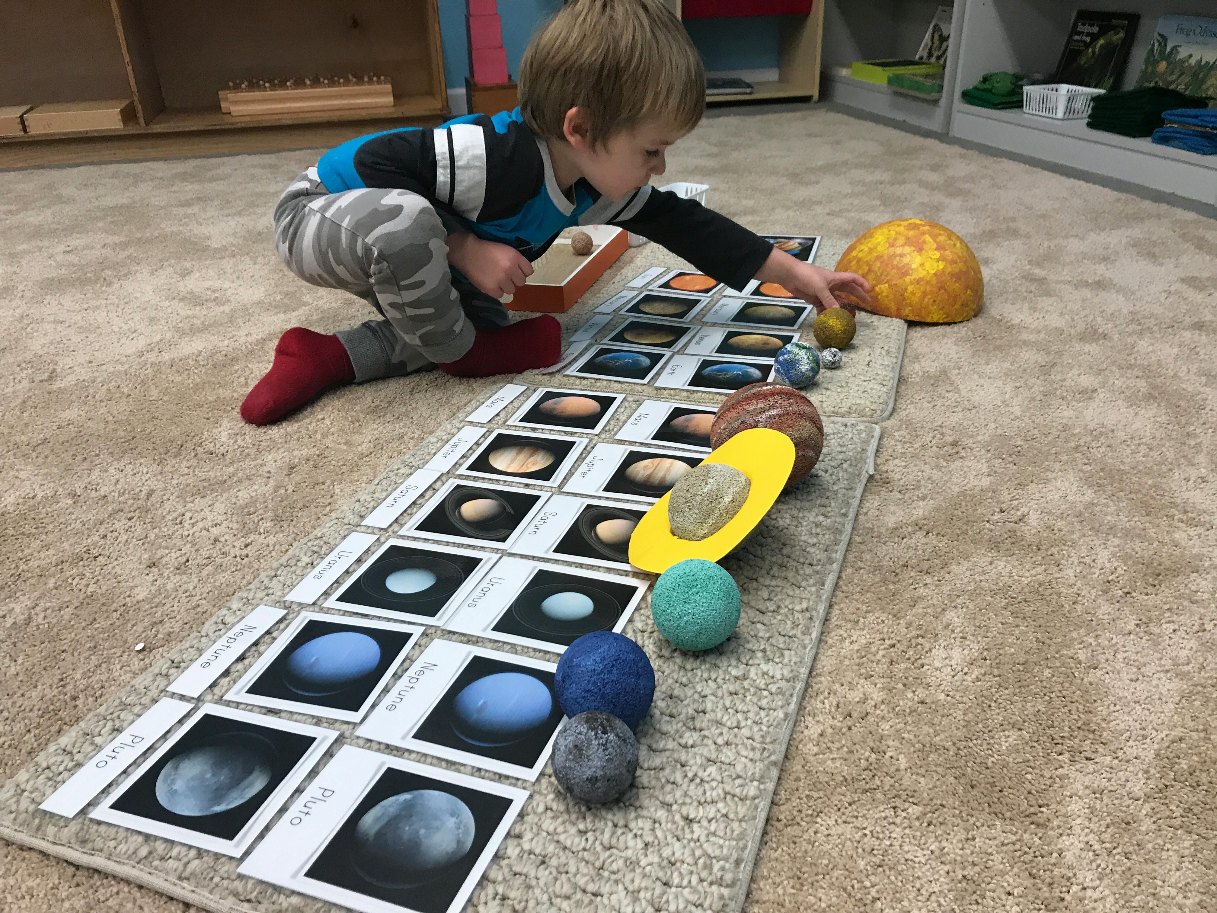 Child playing with planet cards and models on the floor