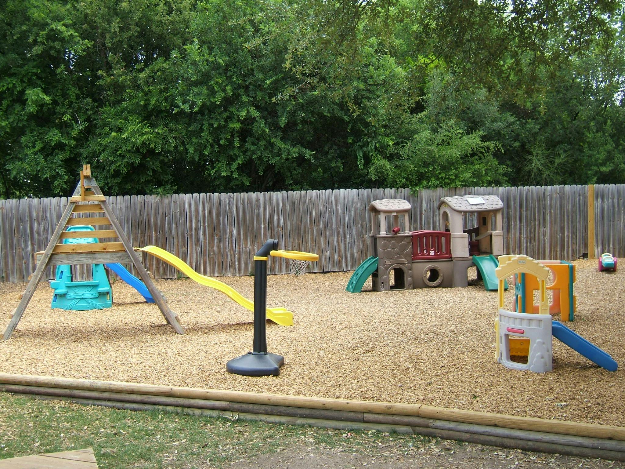 Playground with slides, swings, and play structures on wood chips