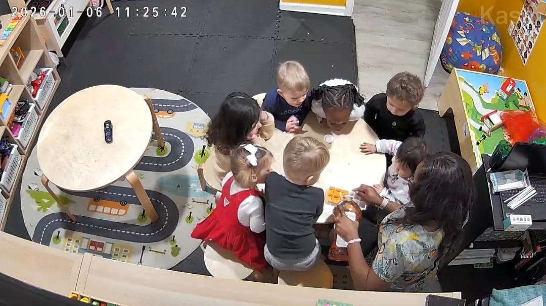 Adult and several children gathered around a table in a classroom