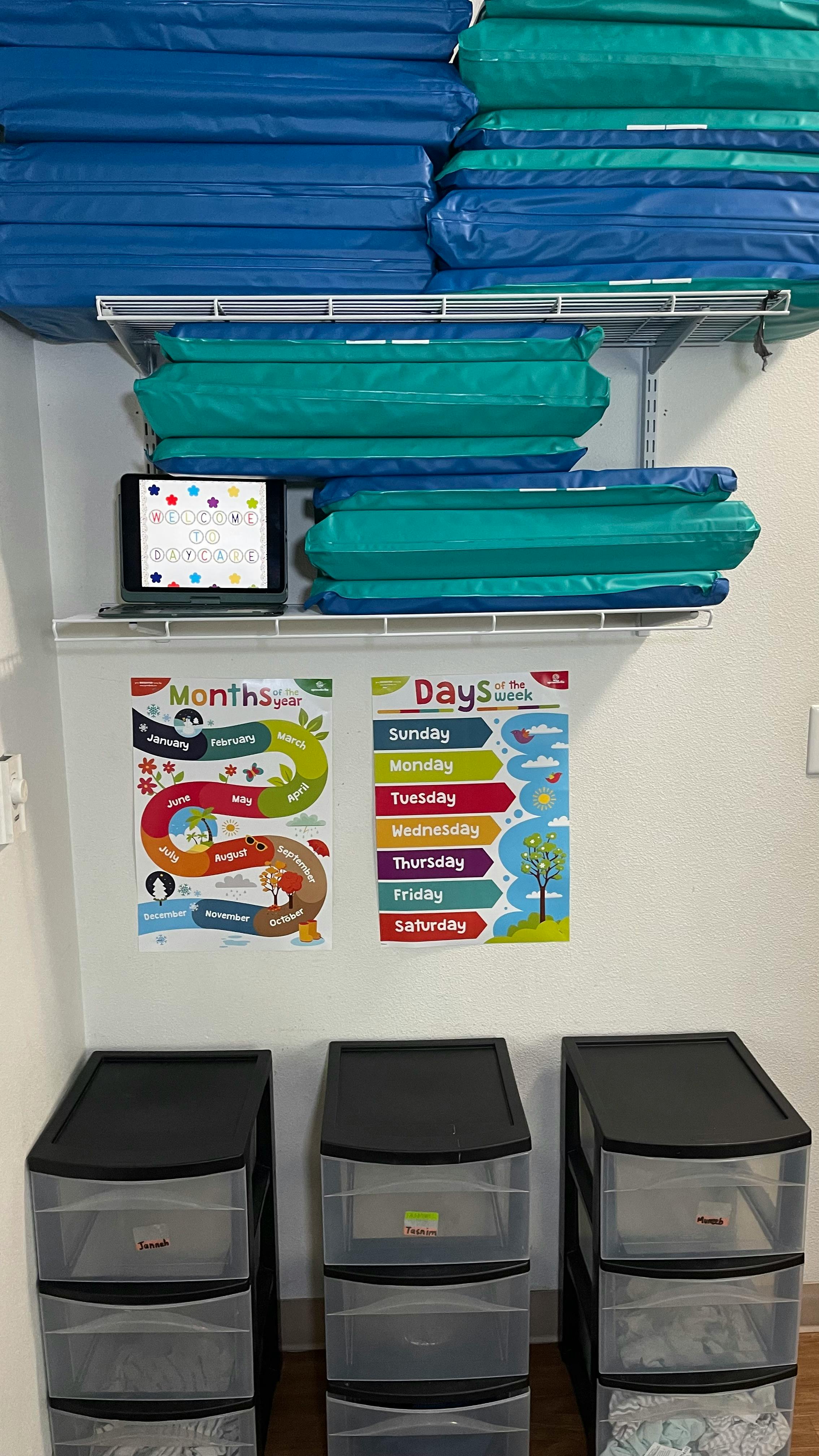 Shelves with blue and green mats, a tablet, and educational posters above plastic drawers