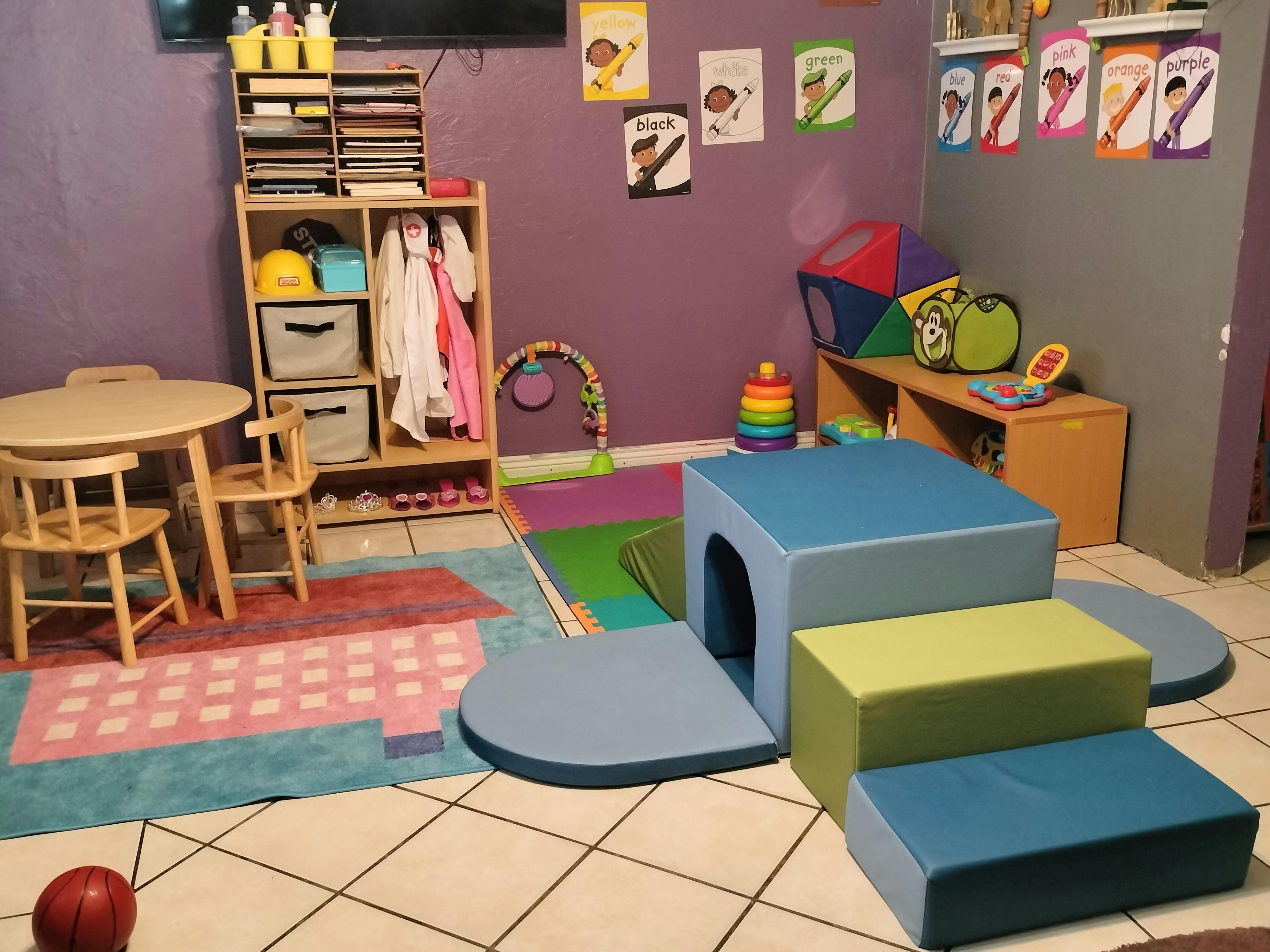 Children's play area with soft play equipment, small table and chairs, and shelves