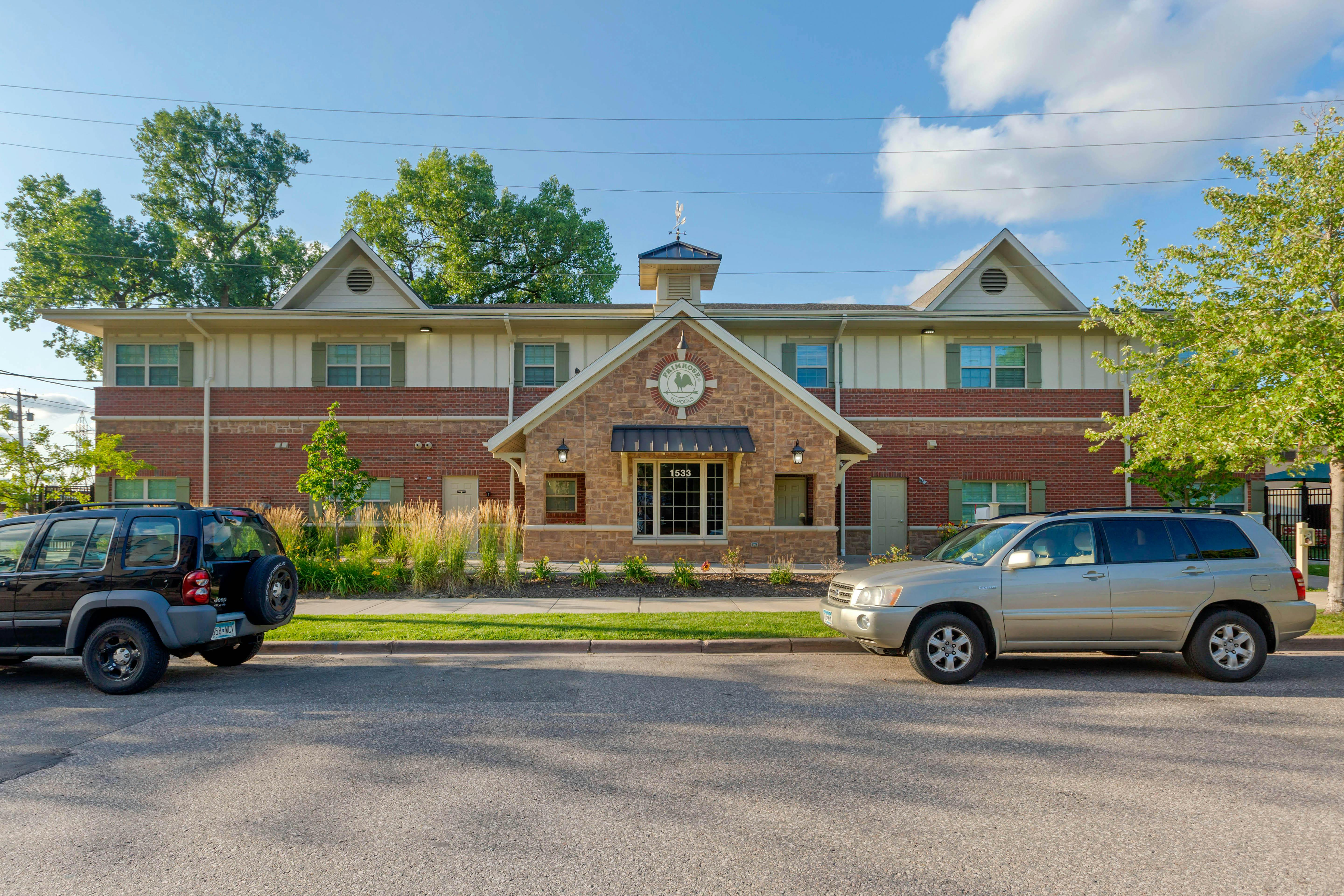 Building with brick and siding facade, two cars parked in front