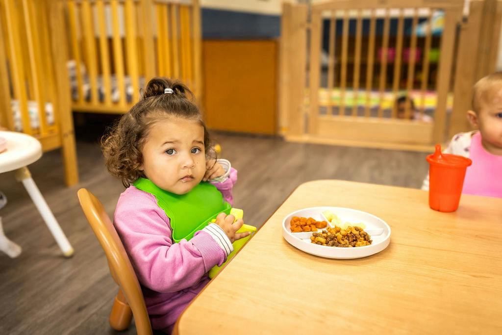 Child sitting at a table with a meal in a childcare setting