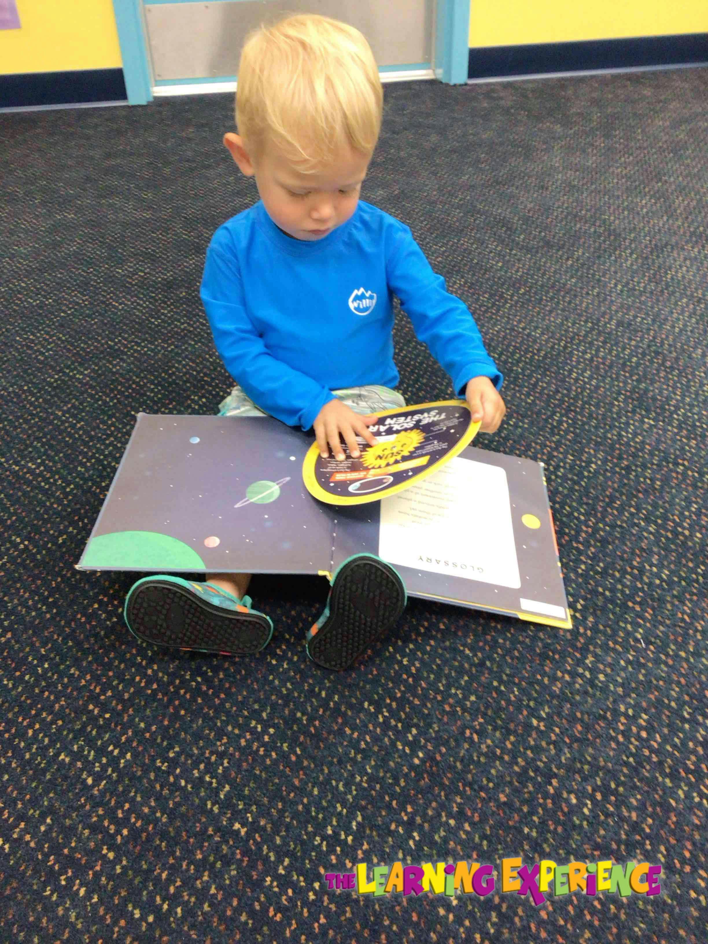 Child sitting on floor looking at a book