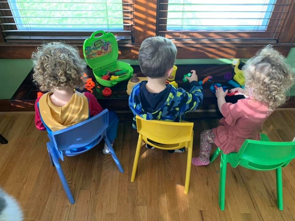 Three children sitting at a table playing with toys