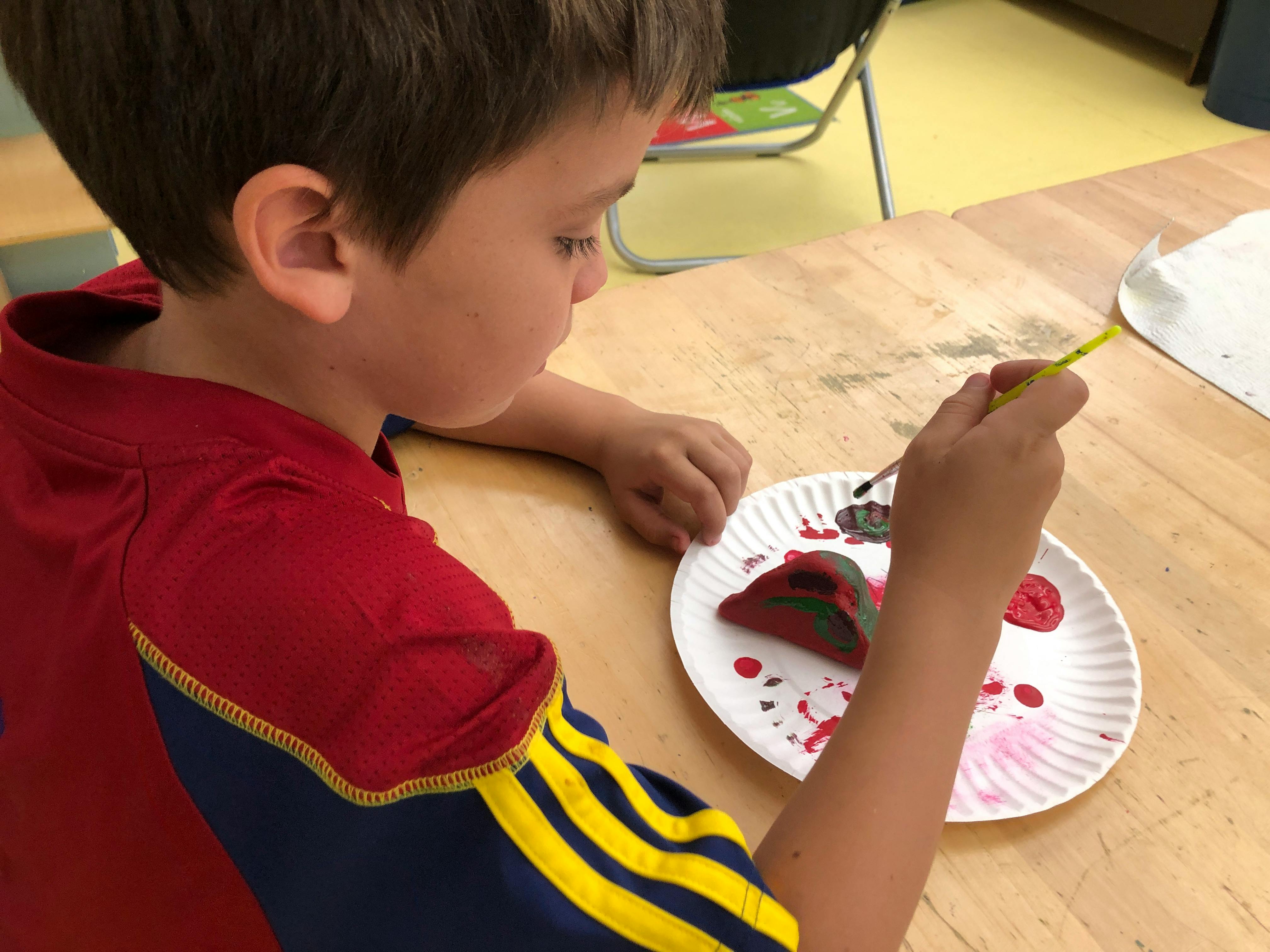 Child painting a craft on a paper plate
