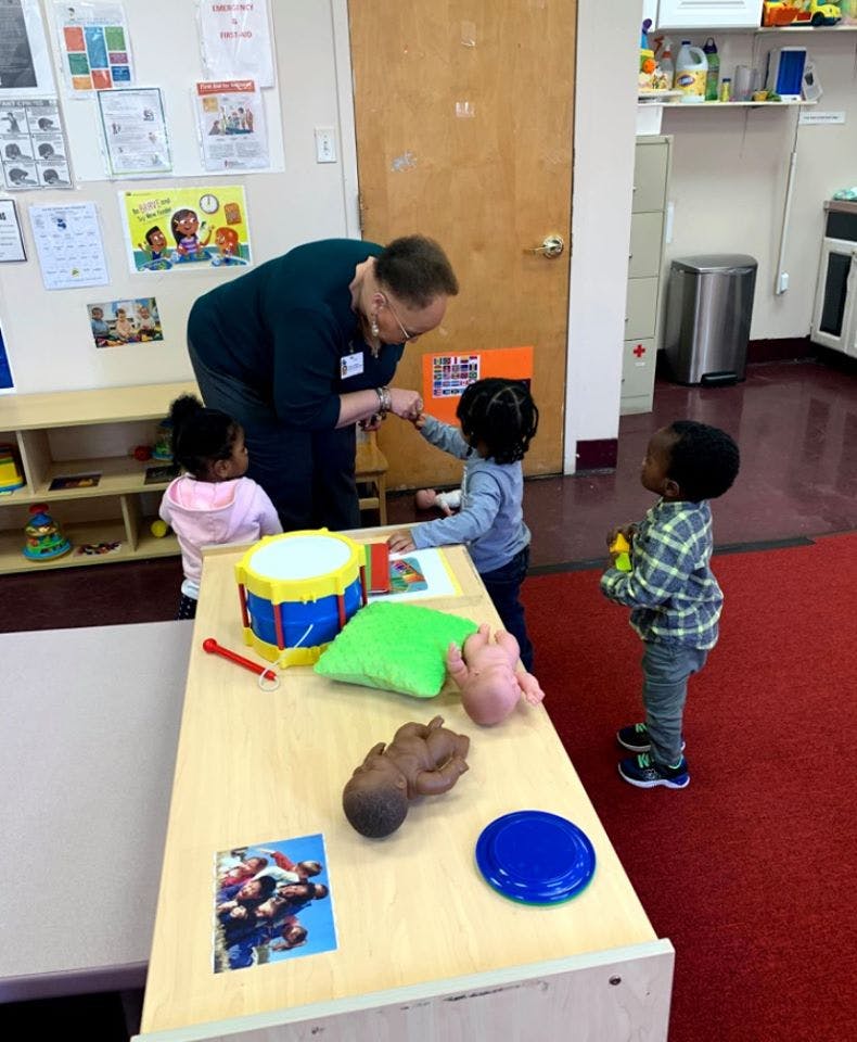 Adult interacting with three children in a classroom