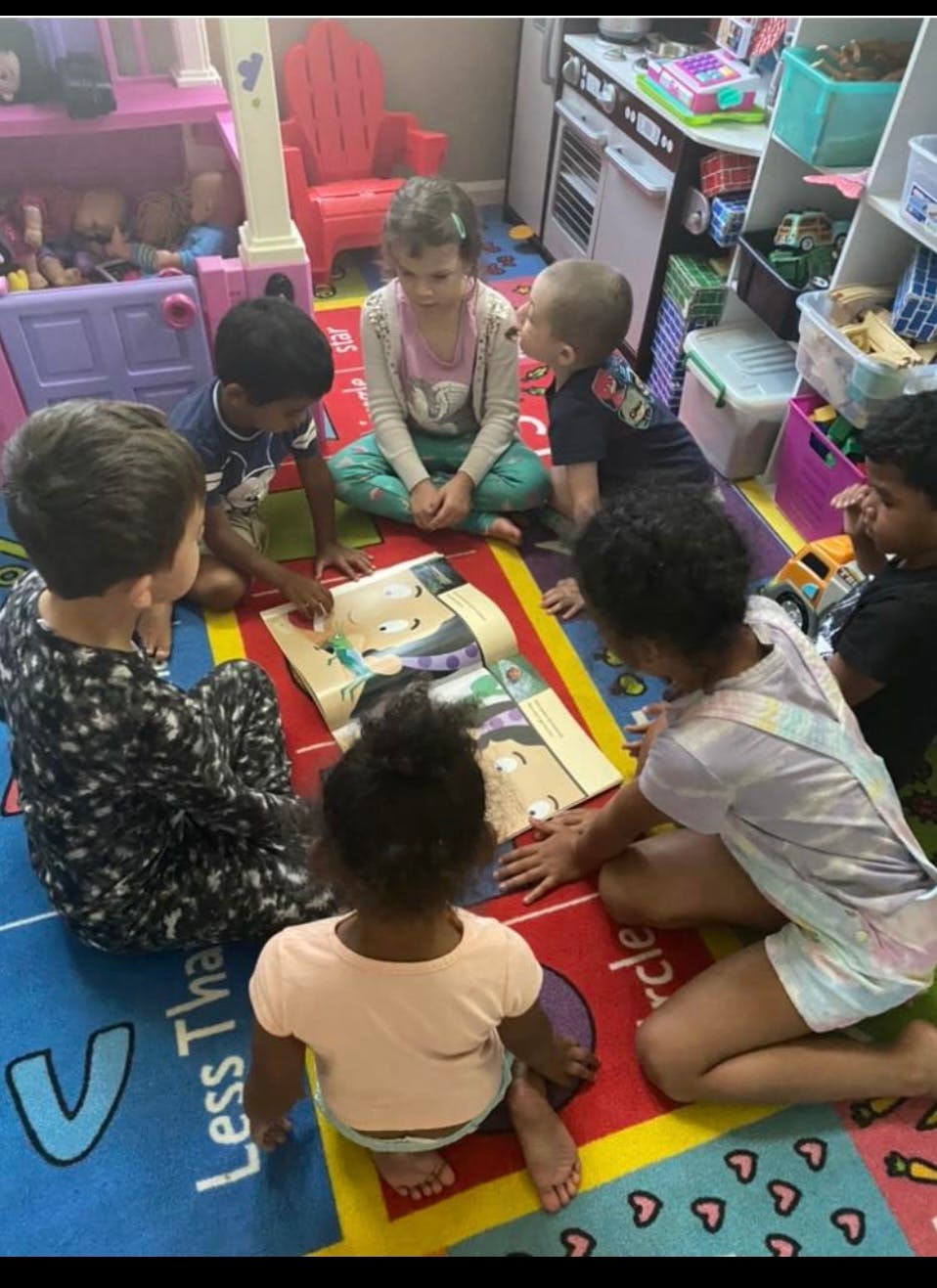 Children sitting on a rug looking at a book