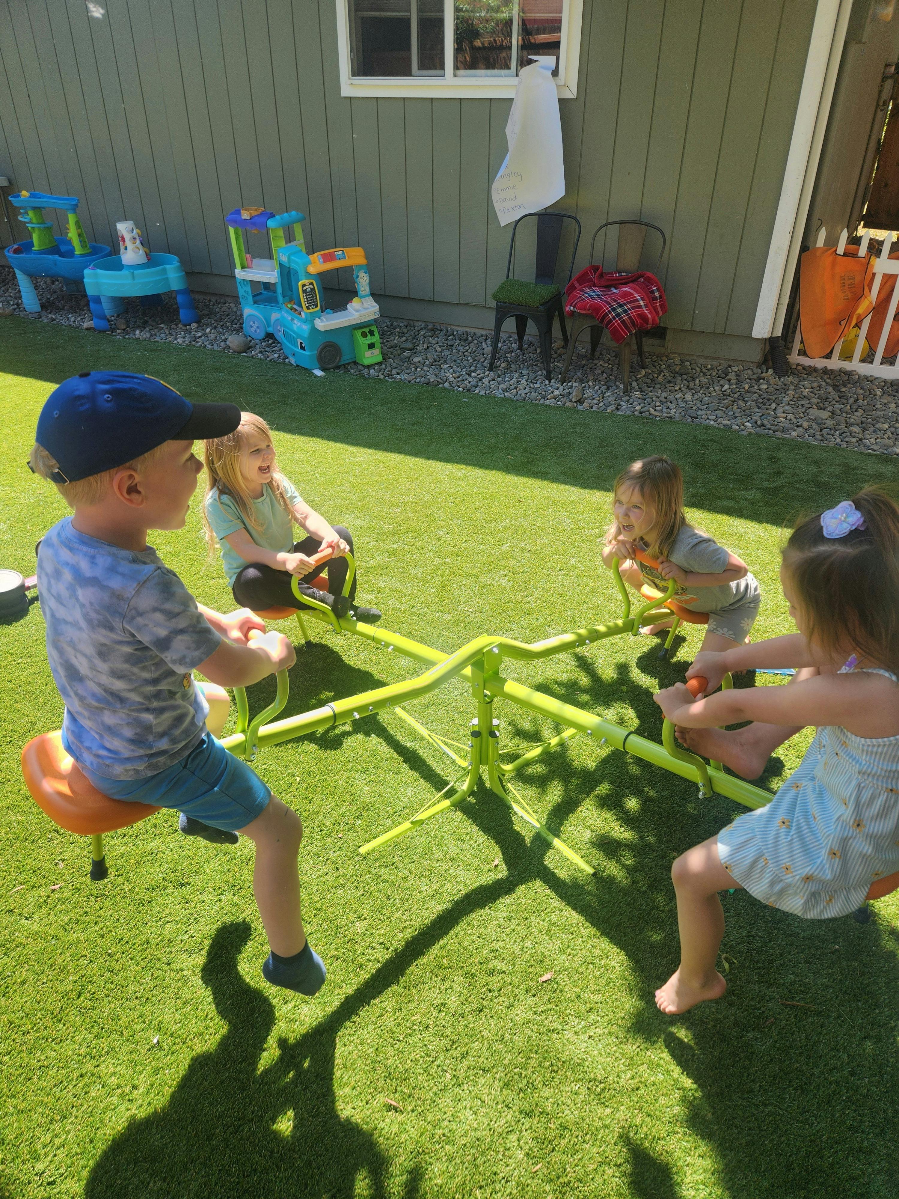 Four children playing on a green seesaw