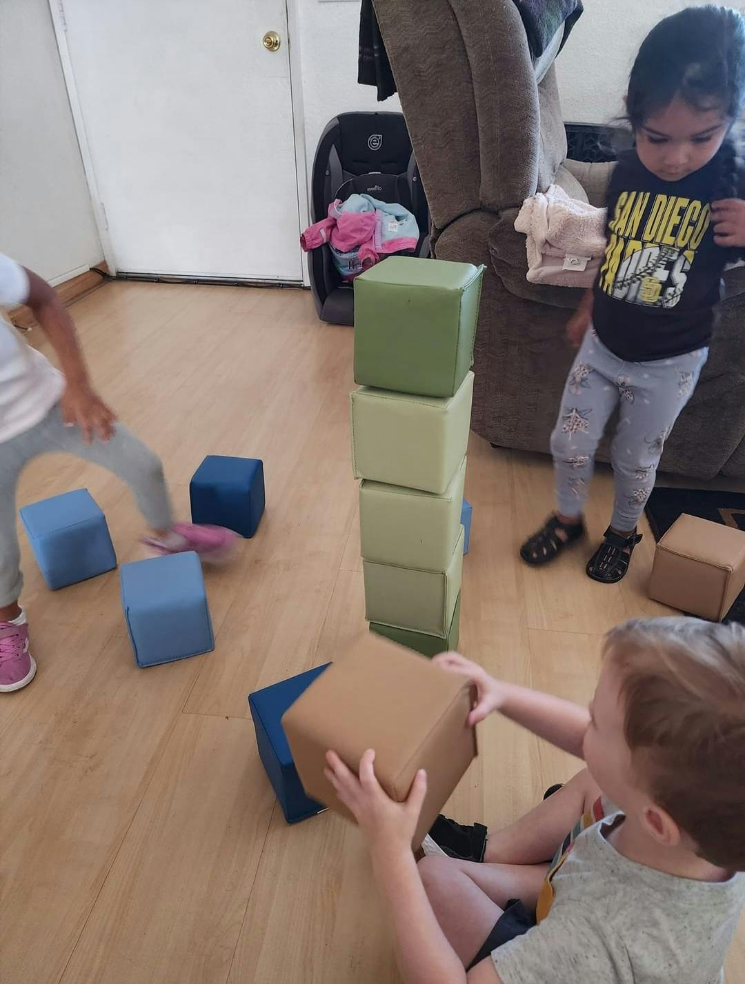 Children playing with soft blocks on a wooden floor