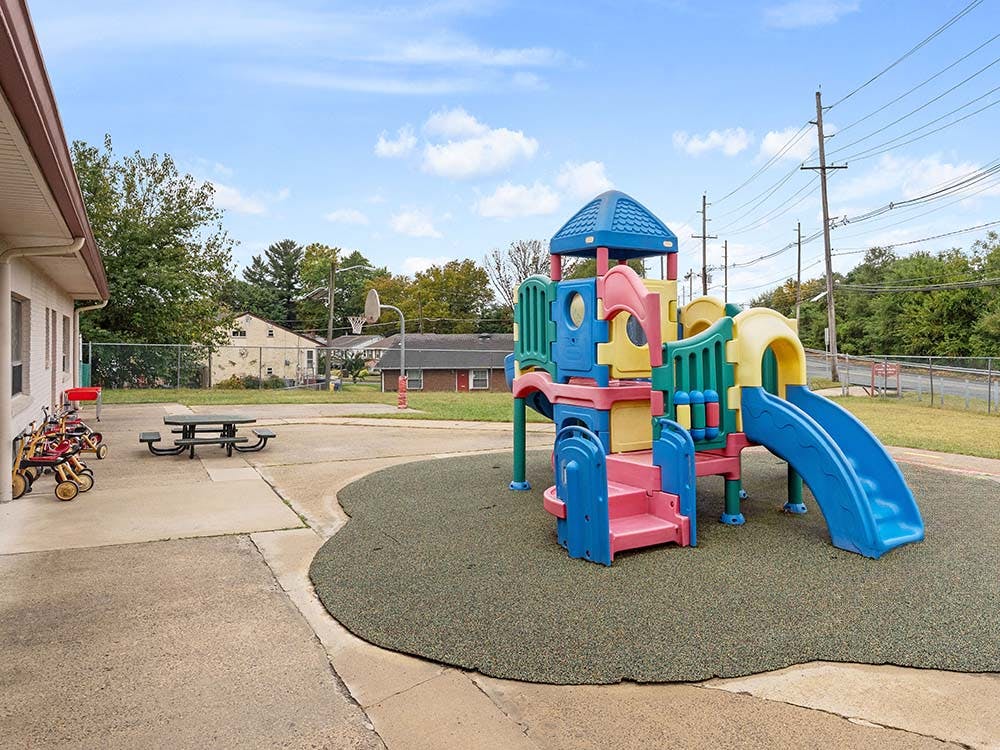 Colorful playground structure on a rubber surface next to a building