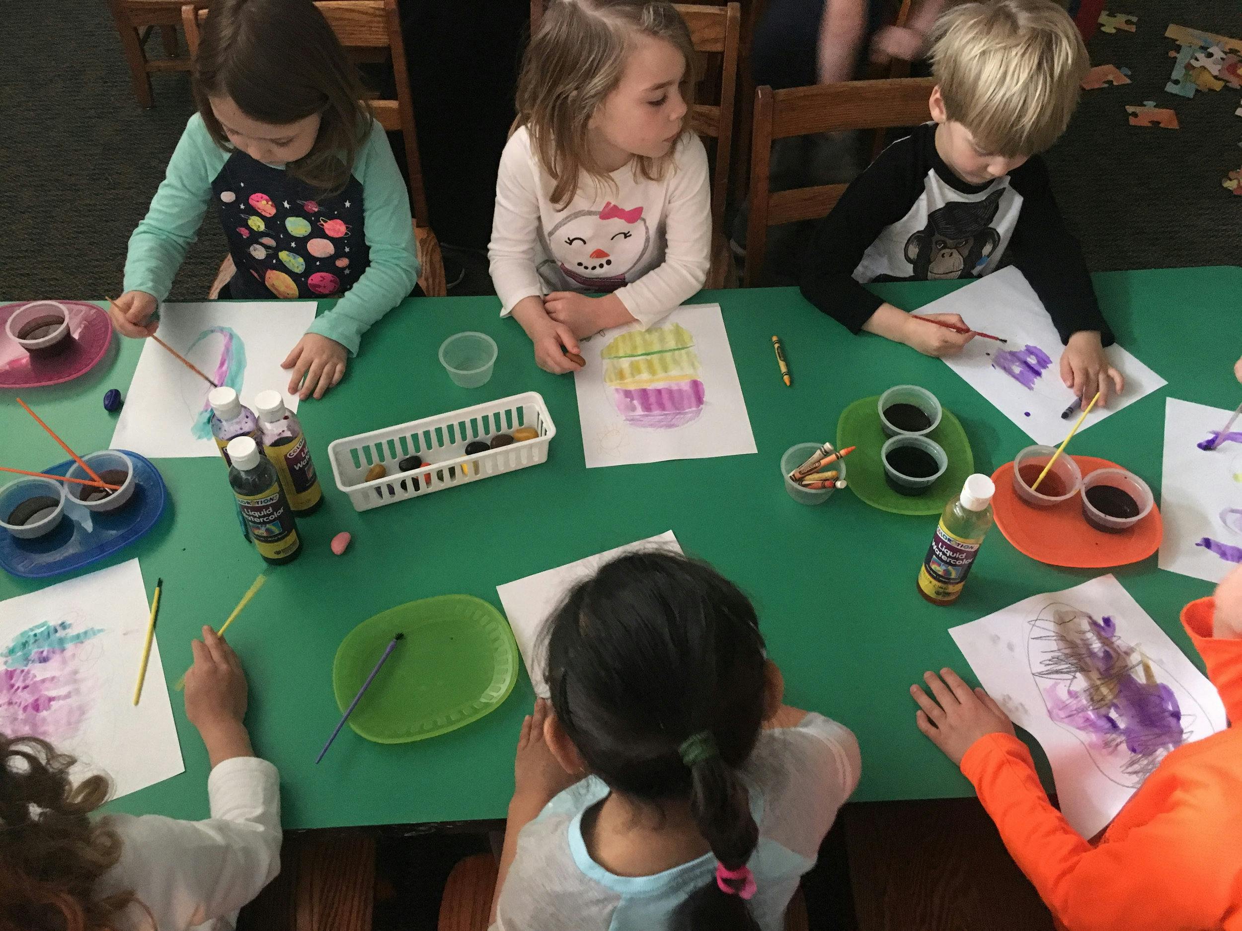 Children painting at a green table