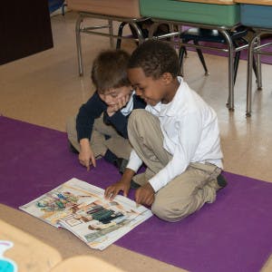 Two children looking at a book on the floor