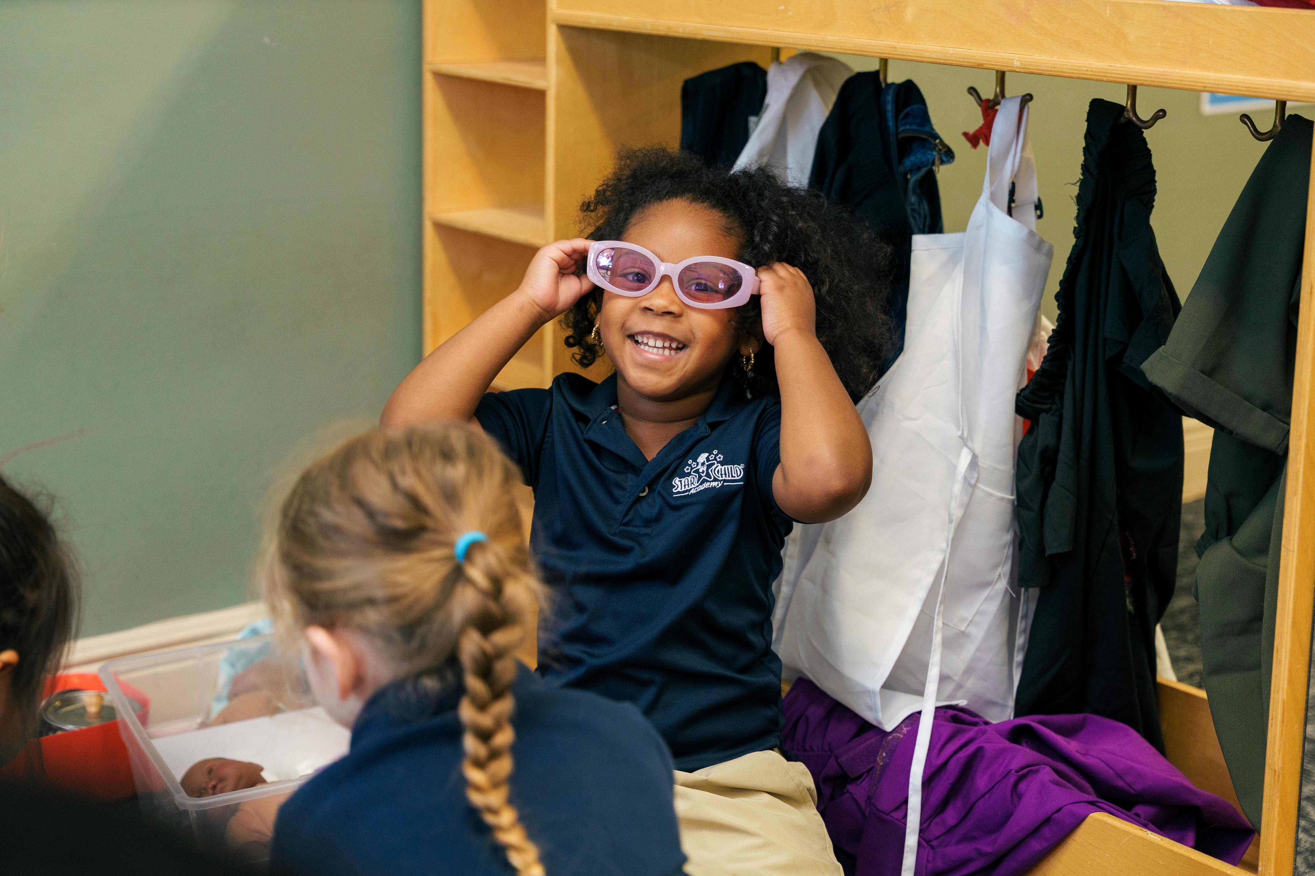 Child wearing pink sunglasses in a classroom