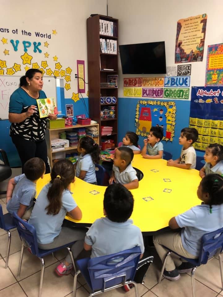 Person reading a book to children in a classroom
