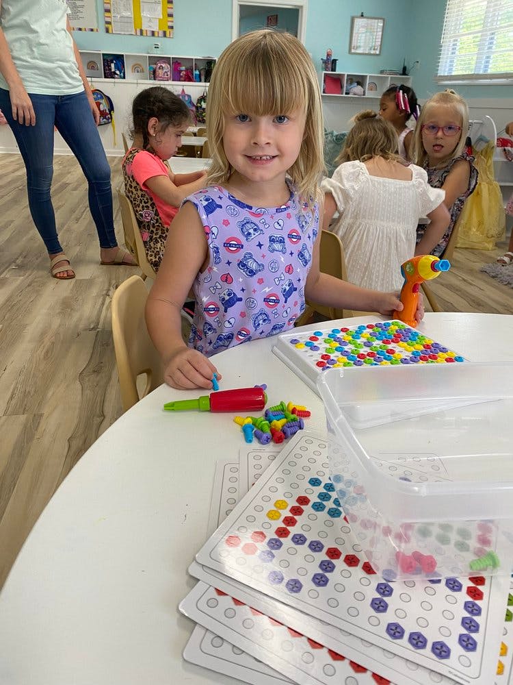 Child playing with colorful pegs and a toy drill at a table