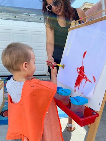Person and child painting on an easel