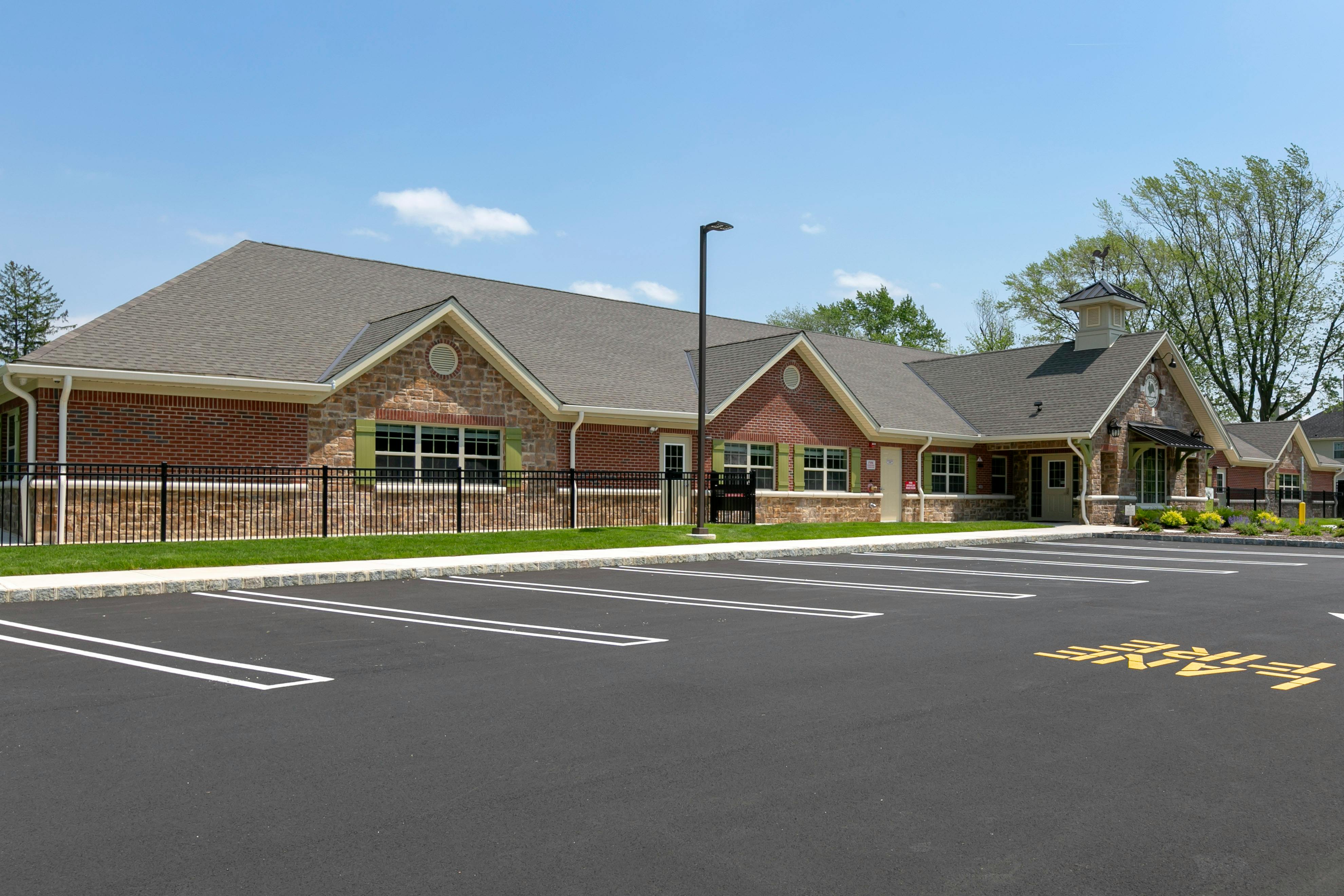 Brick and stone building with a parking lot and grass in front