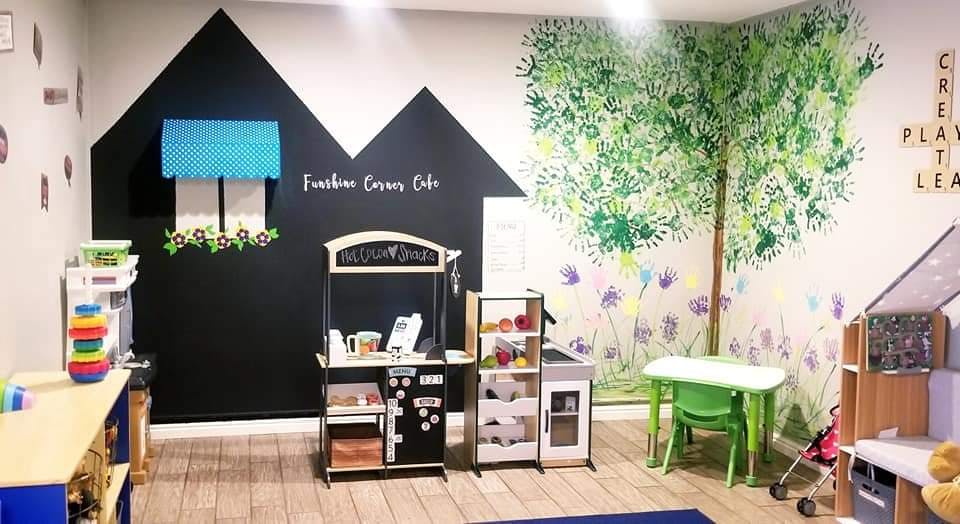 Playroom with a cafe play set and a tree mural on the wall