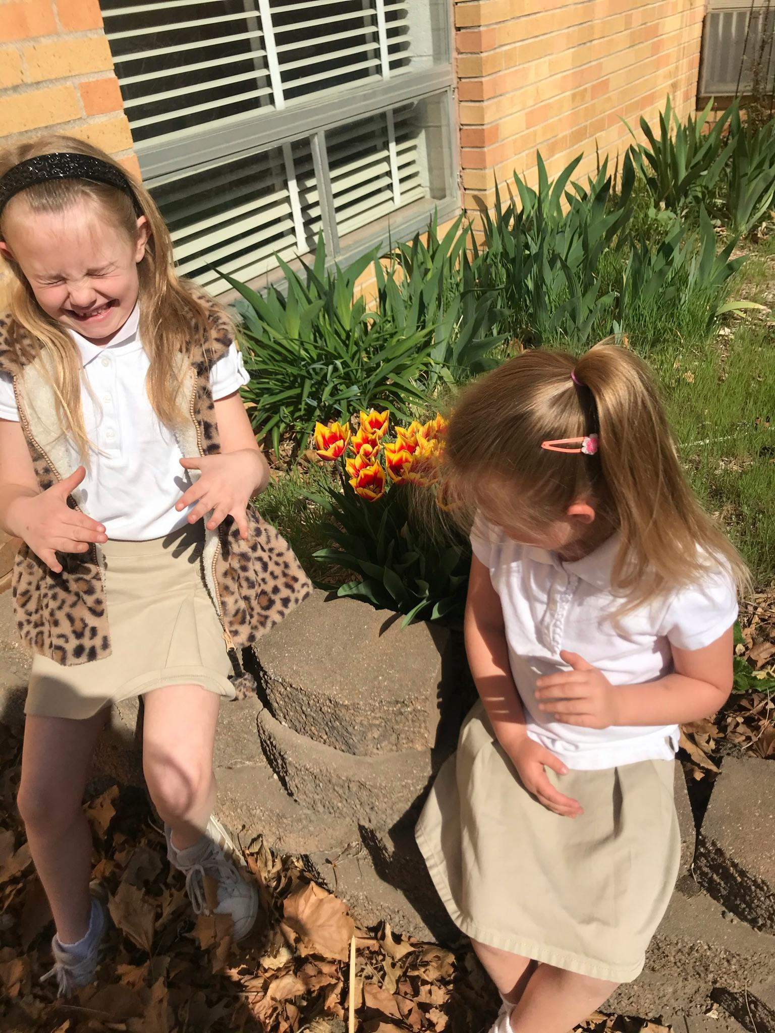 Two children outdoors, one standing and one sitting