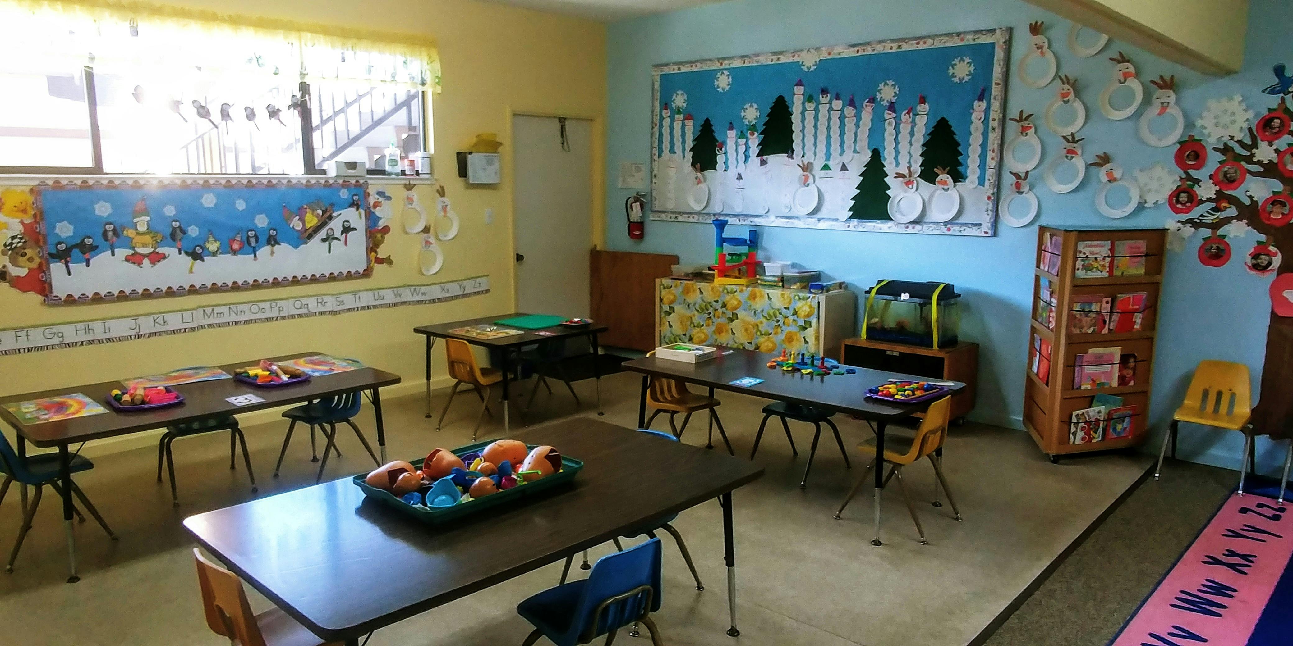 Classroom with small tables and chairs, decorated with winter-themed art