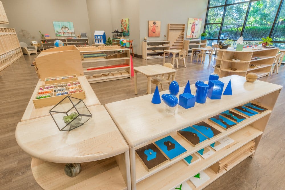 Classroom with wooden shelves, tables, and various learning materials