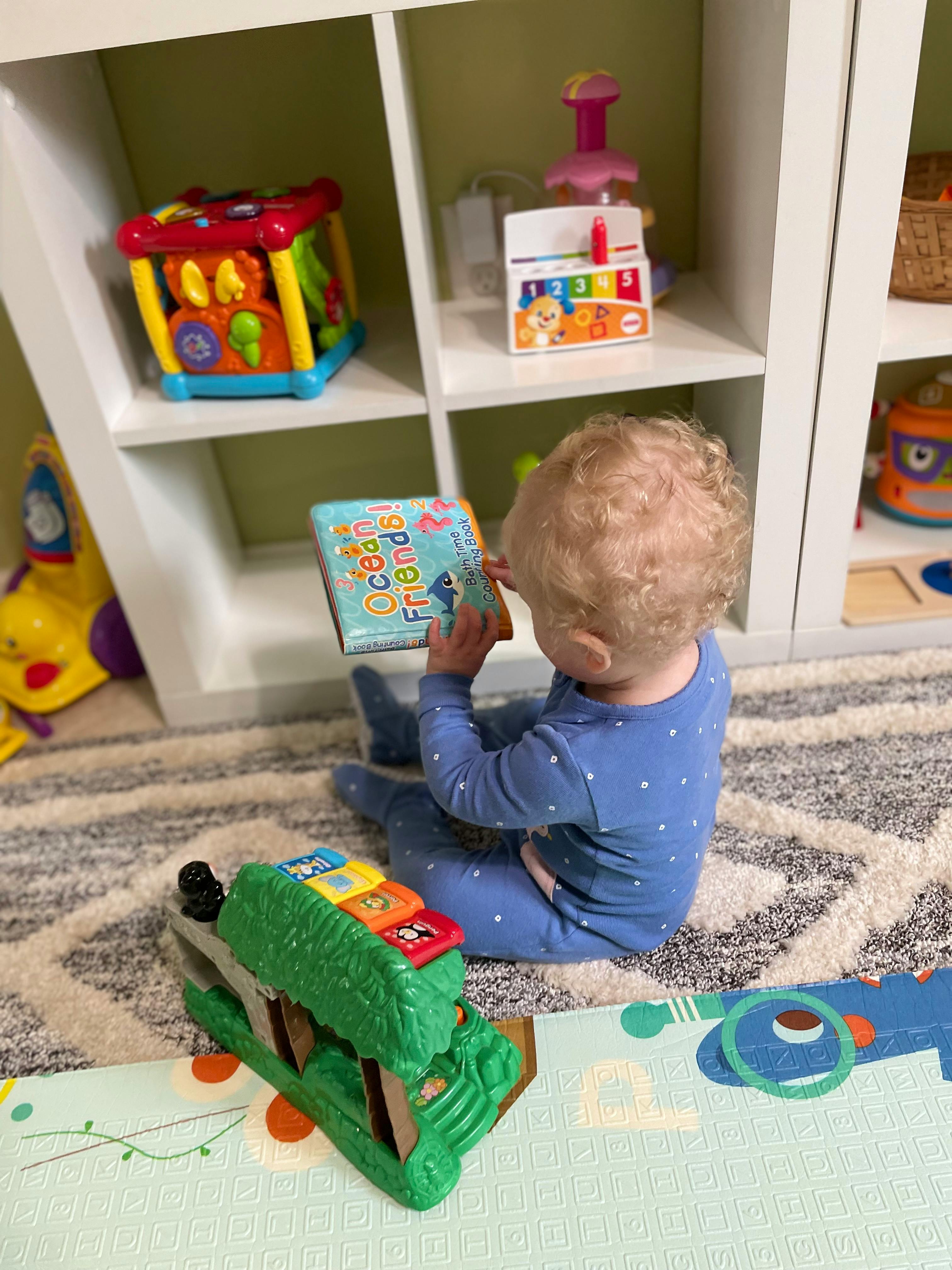 Child sitting on floor reading a book titled "Ocean Friends"