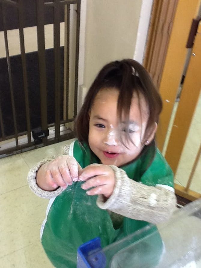 Child with flour on face and hands