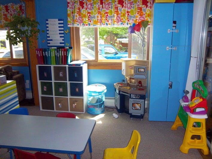Classroom with small table and chairs, storage cubbies, and play kitchen