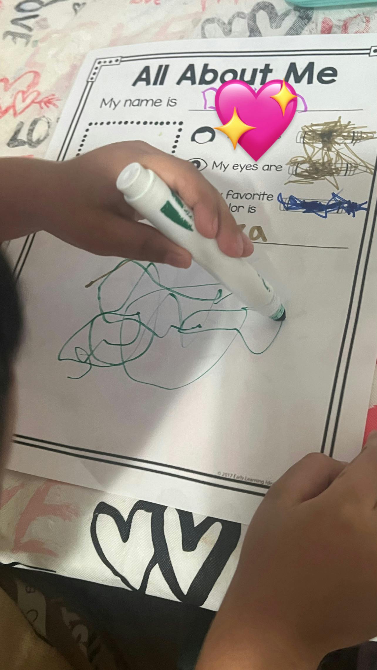Child coloring on an All About Me worksheet with a green marker