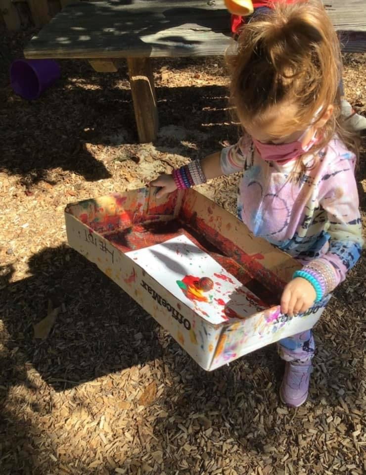 Child holding a box with paint and a paper