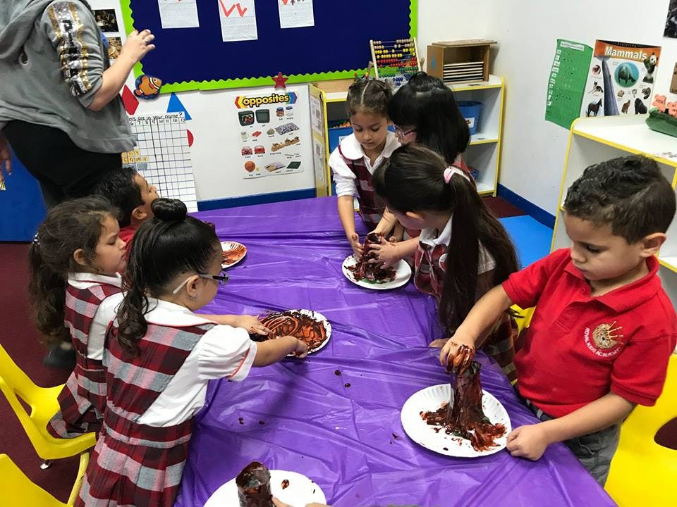 Children making a craft with brown material on plates at a table