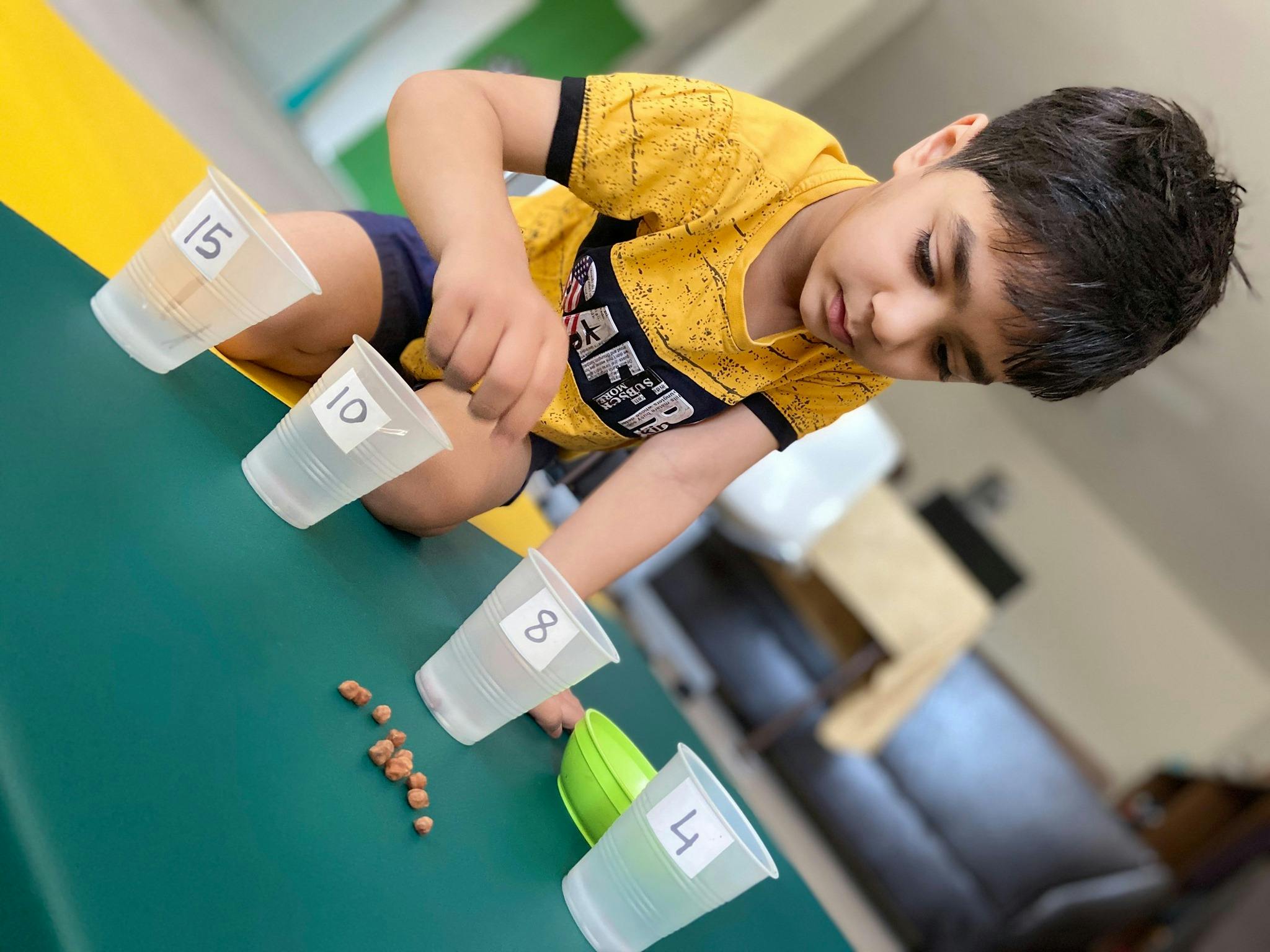 Child playing with numbered cups and small objects