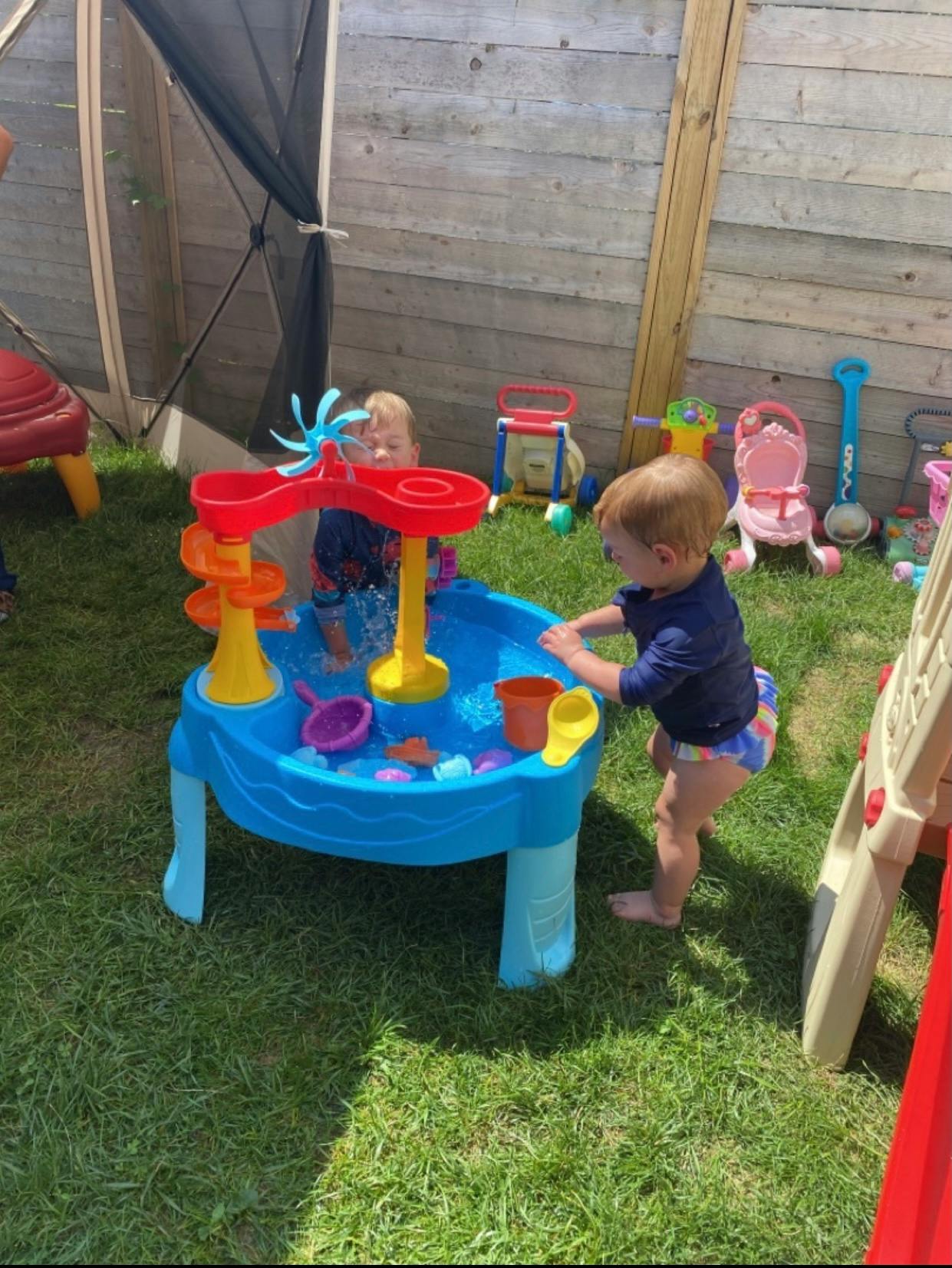 Two children playing at a water table outdoors