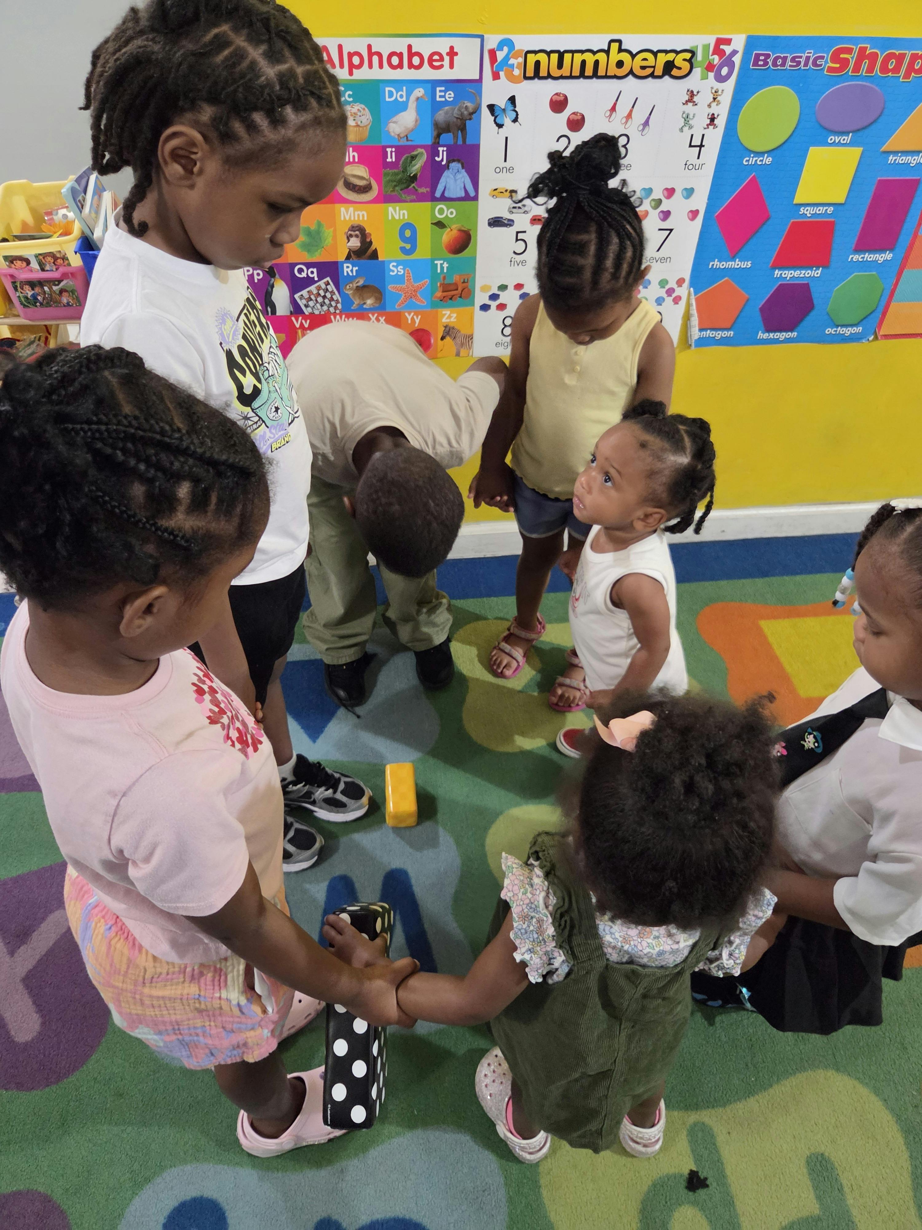 Group of children standing in a circle on a colorful rug in a classroom