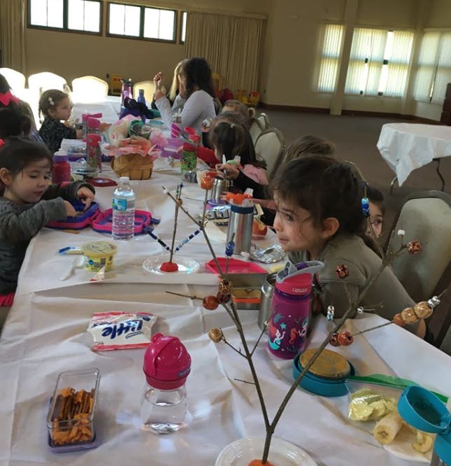 Children sitting at a long table with various items
