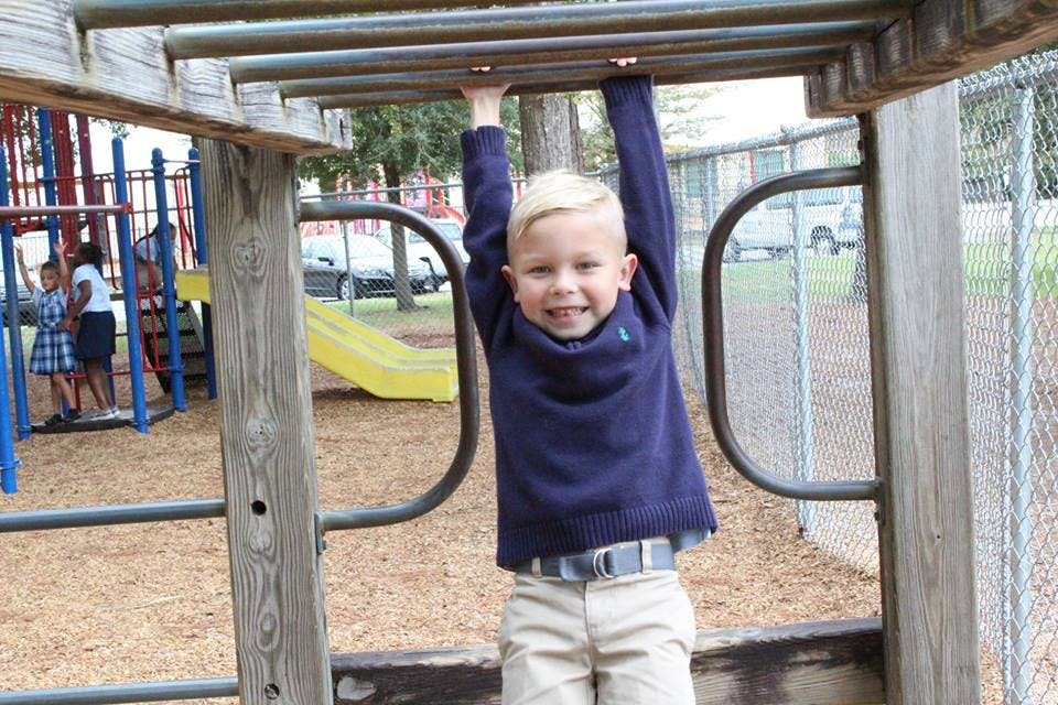 Child hanging from monkey bars on a playground
