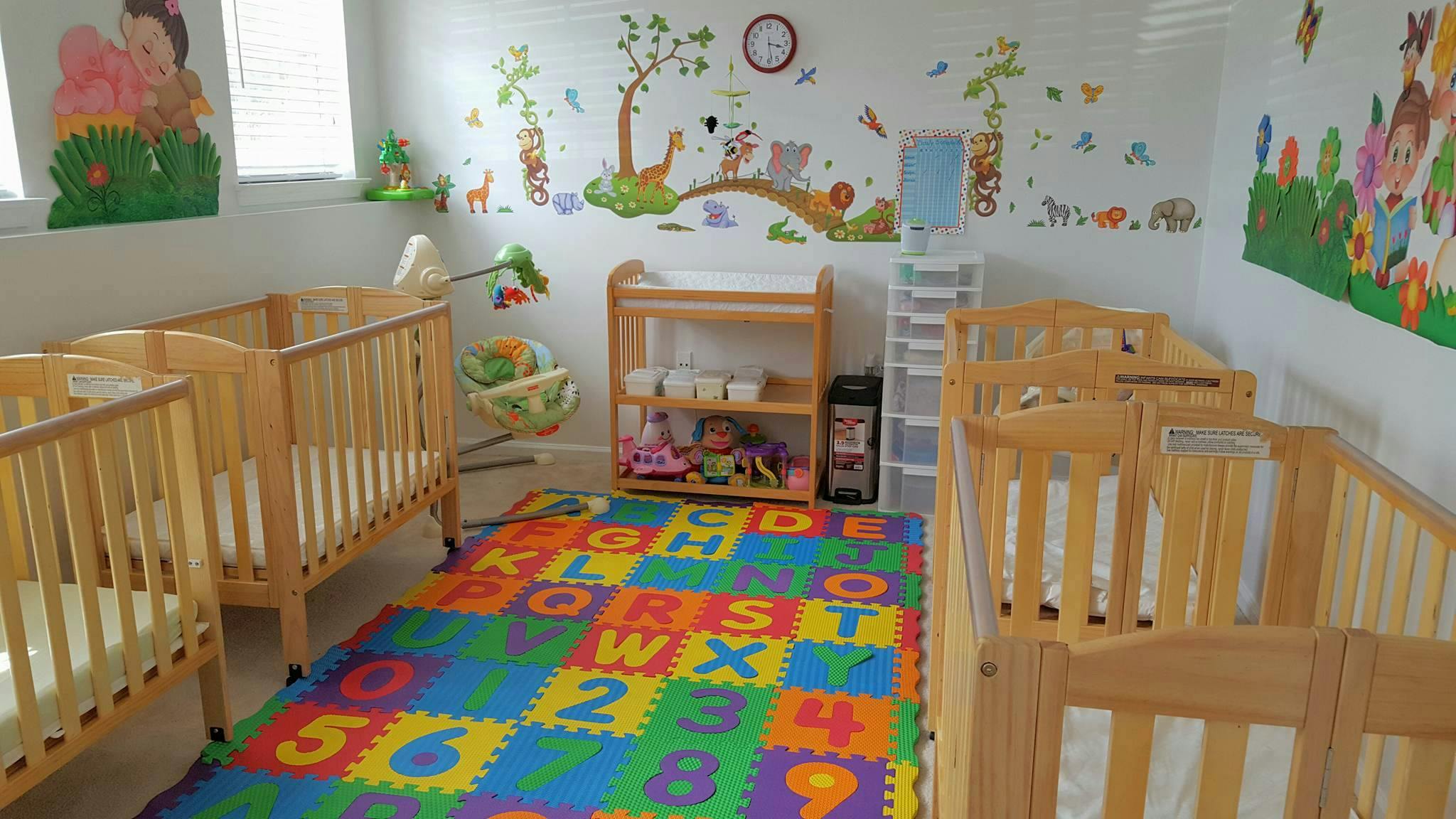 Nursery room with multiple wooden cribs and a colorful alphabet play mat