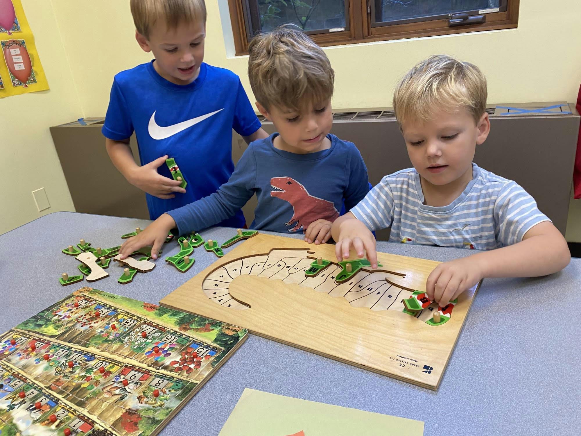 Three children playing with a wooden puzzle at a table