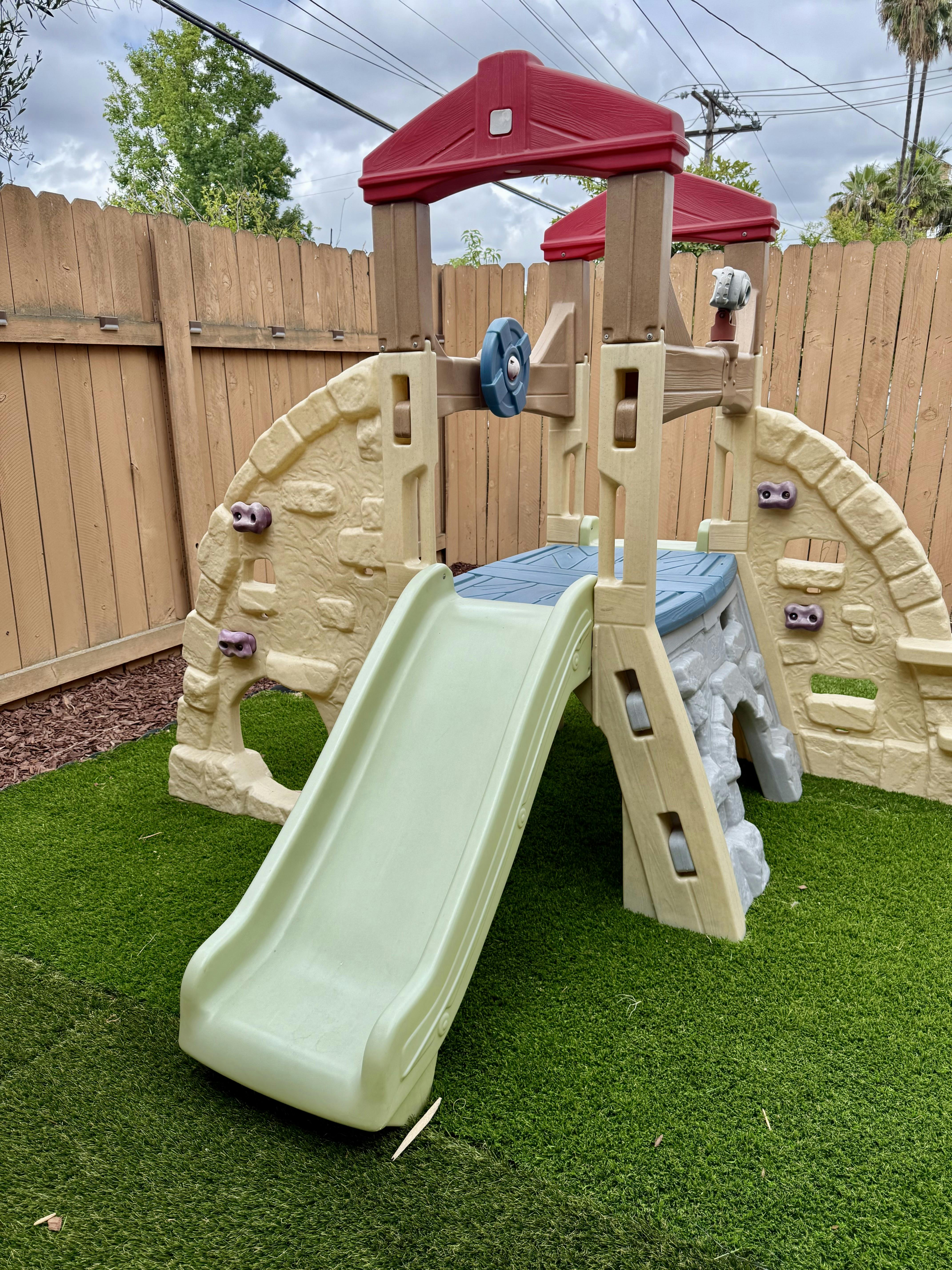 Plastic playground climber with a slide on artificial grass